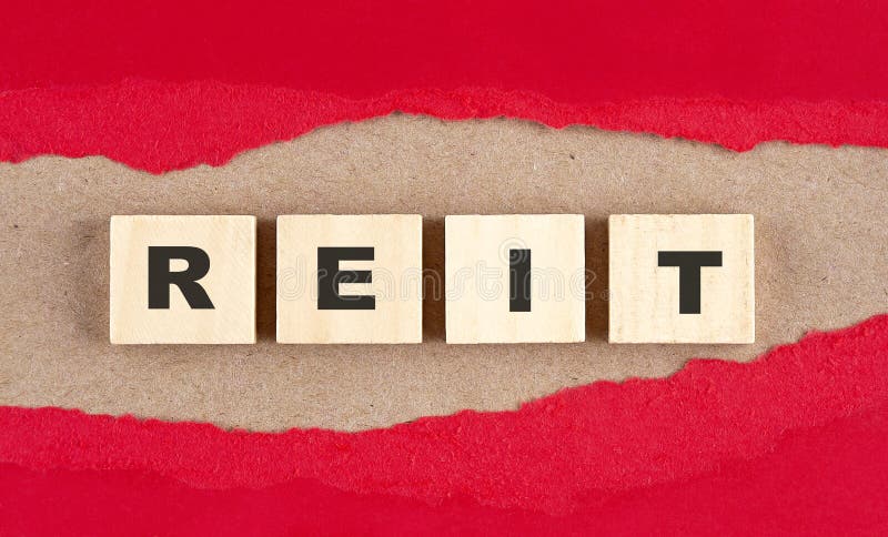 REIT word on wooden cubes on red torn paper , financial concept background stock photo