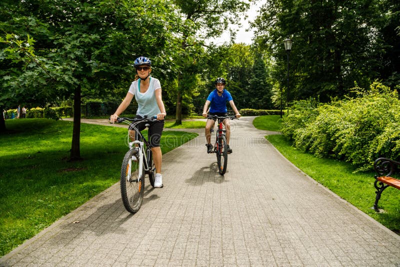 Middle-aged woman and man riding bicycles at summer green park. Middle-aged woman and man riding bicycles at summer green park