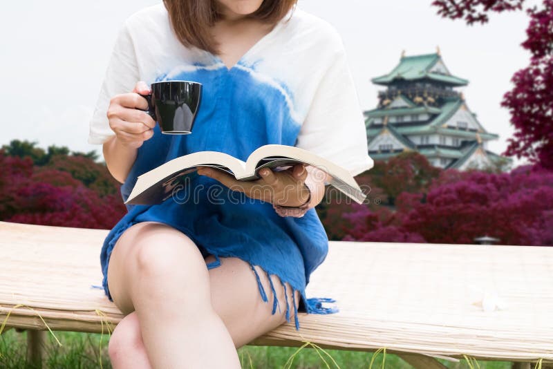 Reizend Mädchensitzen- und -lesebuch Osaka-Schlosshintergrund lizenzfreie stockfotografie Reizend Mädchensitzen- und -lesebuch Osaka-Schlosshintergrund lizenzfreie stockfotografie