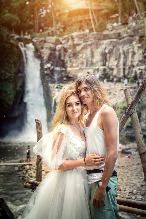 Reizende Hochzeitspaare gegen Wasserfall auf Sonnenuntergang, Tropeninsel von Bali stockfotografie Reizende Hochzeitspaare gegen Wasserfall auf Sonnenuntergang, Tropeninsel von Bali stockfotografie