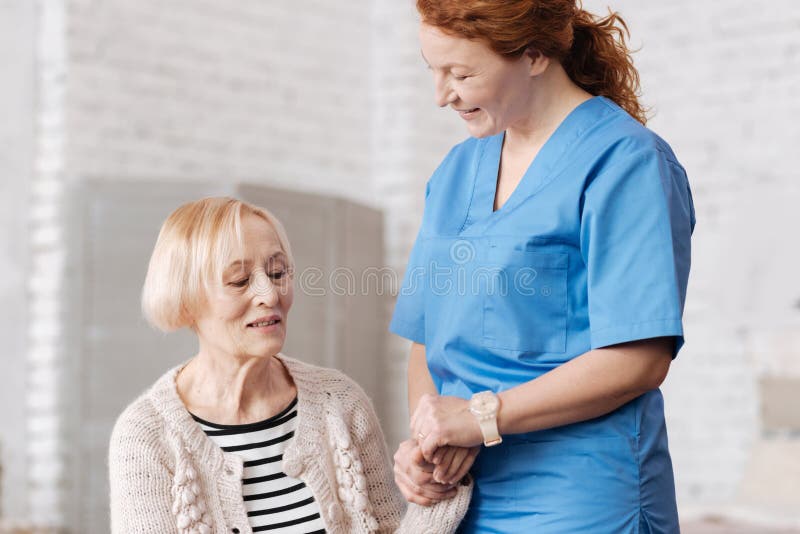 Reizende kompetente Krankenschwester, die ältere Dame stützt stockbild Reizende kompetente Krankenschwester, die ältere Dame stützt stockbild