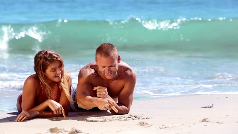 Reizende Paare, die auf Sand liegen