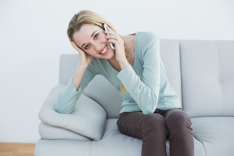 Reizende zufällige anrufende Frau beim Sitzen auf Couch lizenzfreie stockfotos Reizende zufällige anrufende Frau beim Sitzen auf Couch lizenzfreie stockfotos