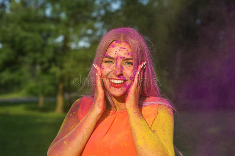 Reizendes blondes Mädchen, das Spaß mit bunter trockener Farbe am Park hat Konzept für Festival Holi lizenzfreie stockbilder Reizendes blondes Mädchen, das Spaß mit bunter trockener Farbe am Park hat Konzept für Festival Holi lizenzfreie stockbilder