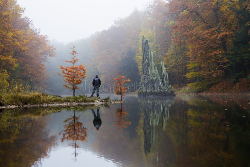 Traveler near Rakotzbrücke (Devil's bridge) in early morning mist, in autumn, Kromlau, Germany. Traveler near Rakotzbrücke (Devil's bridge) in early morning mist, in autumn, Kromlau, Germany