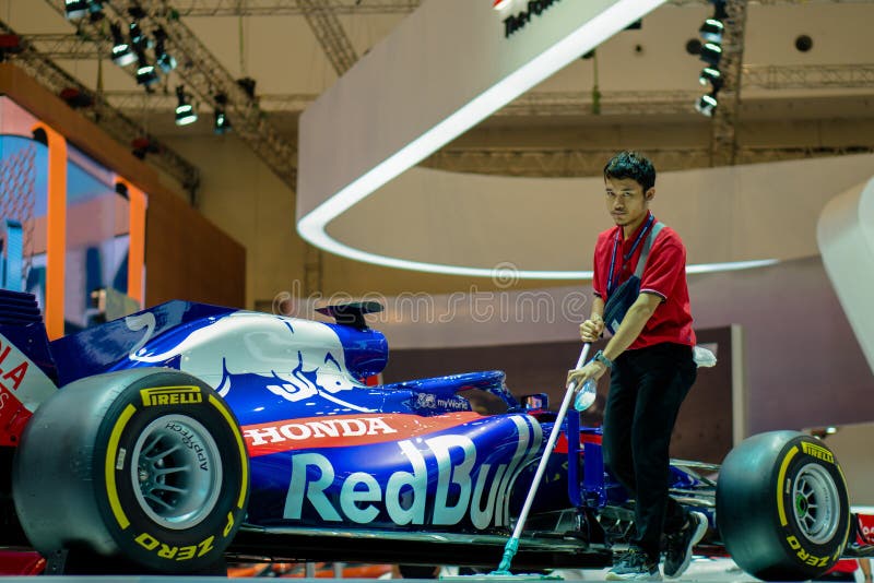 Tangerang, Indonesia - July 19, 2019: The clerk cleans the floor in exhibition area. Near the Formula 1 Honda Red Bull race car in Gaikindo Indonesia International Auto Show GIIAS 2019. Tangerang, Indonesia - July 19, 2019: The clerk cleans the floor in exhibition area. Near the Formula 1 Honda Red Bull race car in Gaikindo Indonesia International Auto Show GIIAS 2019.