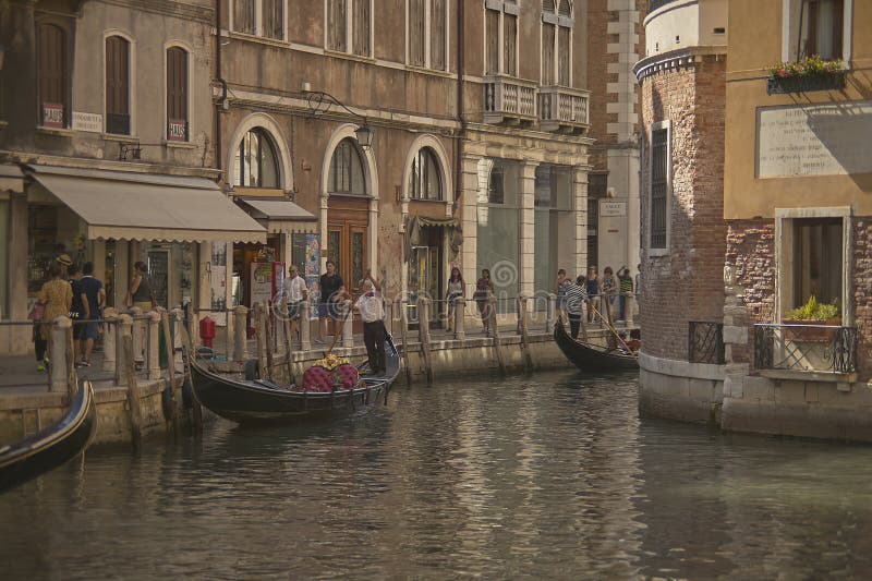 A glimpse of Venice with tourists walking and gondola sailing through the water. A glimpse of Venice with tourists walking and gondola sailing through the water.