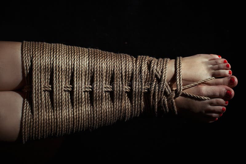 Female legs tied with a rope with a pattern. 