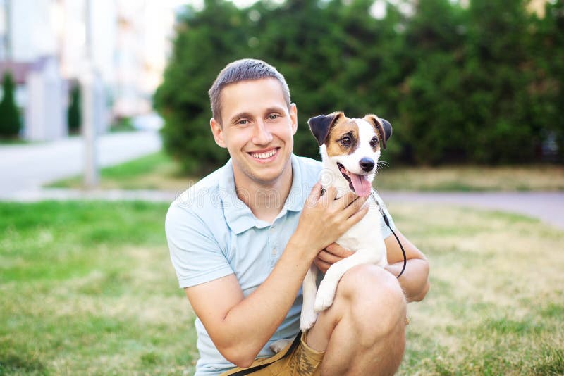 Relation étroite entre le chien et son propriétaire Le propriétaire heureux marche avec un chien et une caresse adorables de Jack images stock Relation étroite entre le chien et son propriétaire Le propriétaire heureux marche avec un chien et une caresse adorables de Jack images stock