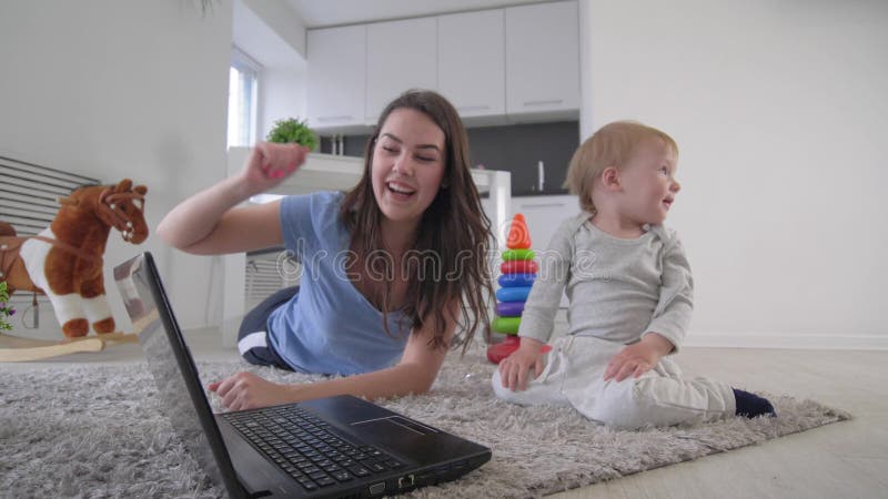 relations de Mère-enfant, maman heureuse avec les bandes dessinées de observation de beau bébé garçon sur des mains d'ordinateur
