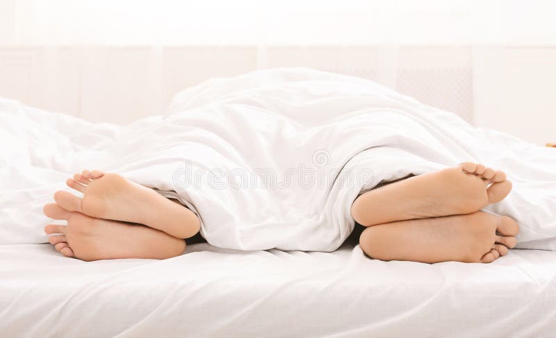 Bare feet of couple sleeping separately in bed royalty free stock photography