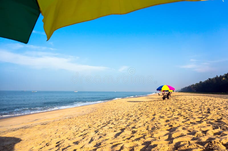 Relax on the beach under umbrellas in the shade. Beach chairs on the white sand beach with cloudy blue sky and sun.