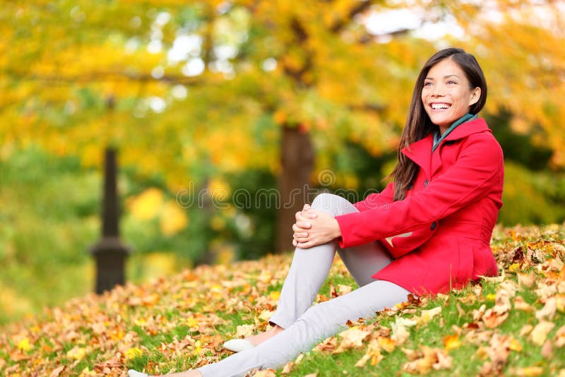 Relaxamento da mulher da queda feliz na folha da floresta do outono
