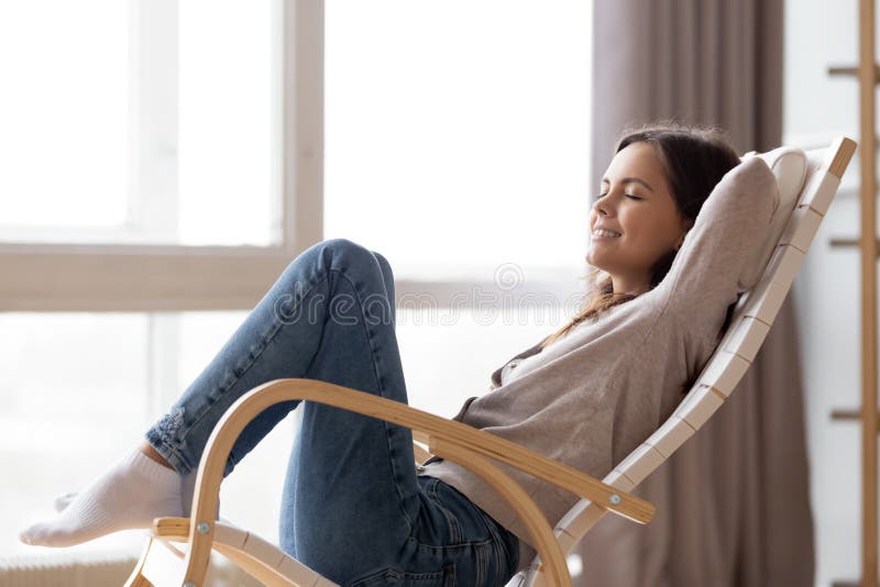 Relaxed calm young woman lounging sitting in comfortable rocking chair