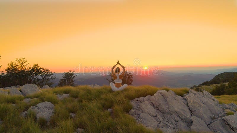 Relaxed female tourist enjoying the summer morning by doing yoga at sunrise.