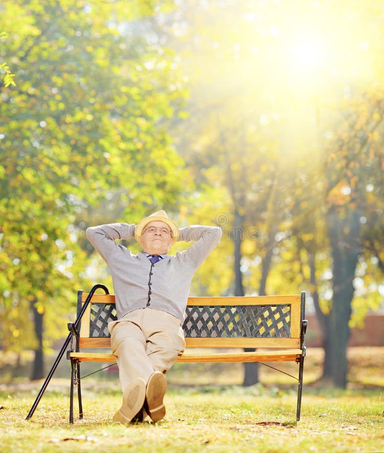 Relaxed senior gentleman sitting on bench in park on a sunny day