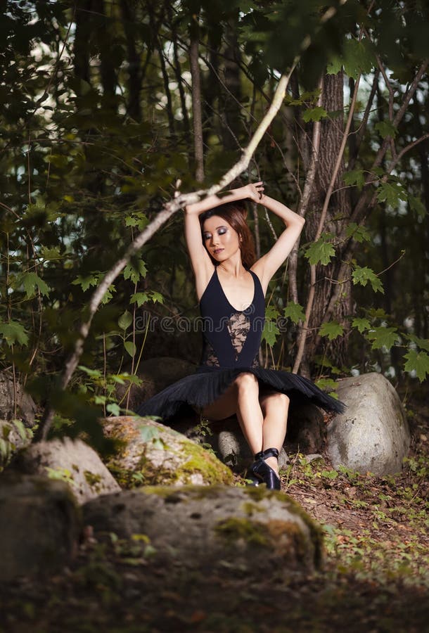 Relaxed Shy And Sexy Young Japanese Ballet Dancer in Black Tutu Posing in Summer Forest and Dreaming With Lifted Hands Behind