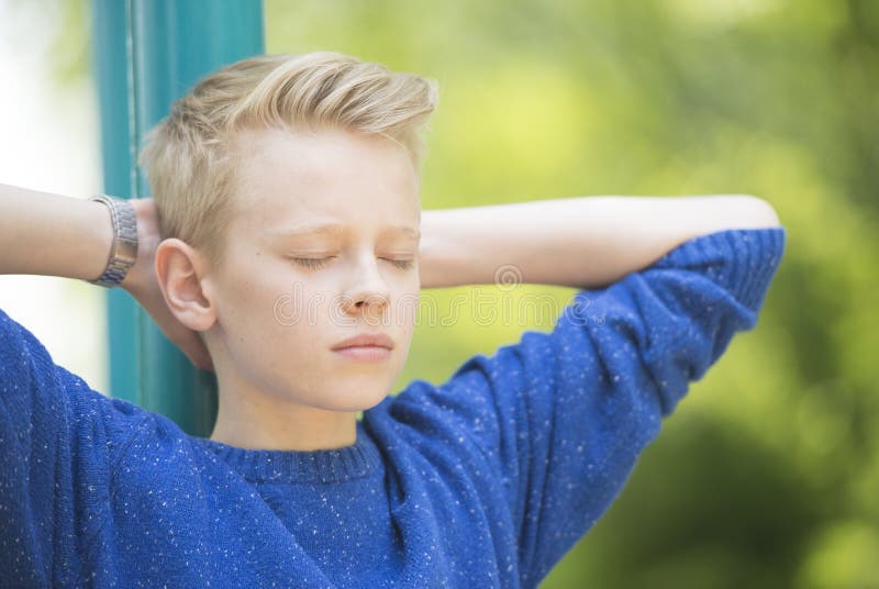 Relaxed teenager boy with closed eyes outdoor