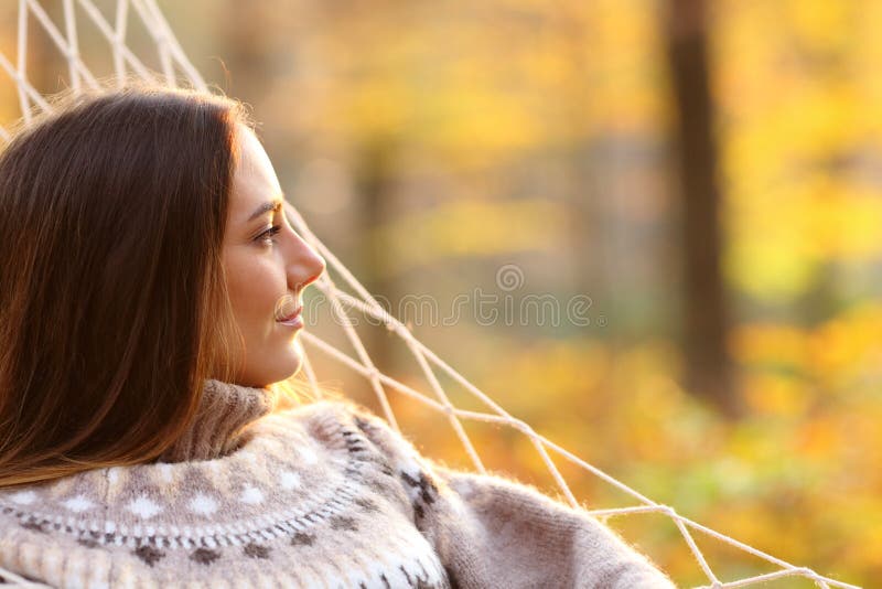 Relaxed woman contemplating on hammock in autumn