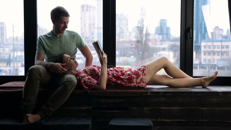 Relaxed young couple reading book together at home