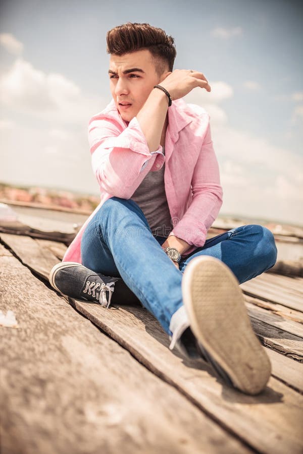 relaxed young fashion man sitting outdoor looks away camera 41025096