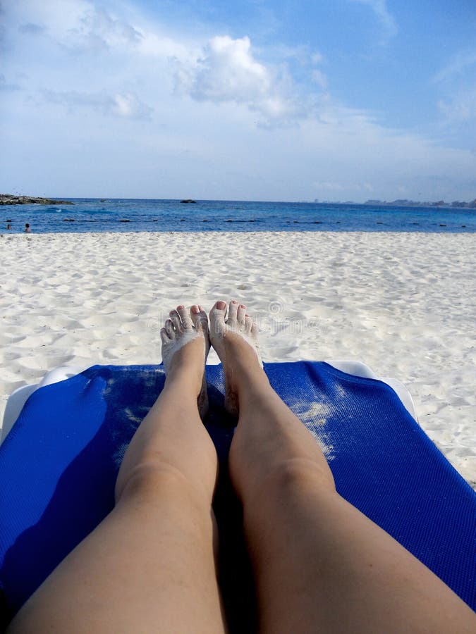 My view of relaxing on the empty tropical beach. Lying on a lounge chair with sandy feet, soaking up some rays. My view of relaxing on the empty tropical beach. Lying on a lounge chair with sandy feet, soaking up some rays.