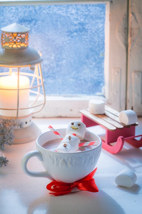 Relaxing in hot cocoa snowman for Christmas by frozen window