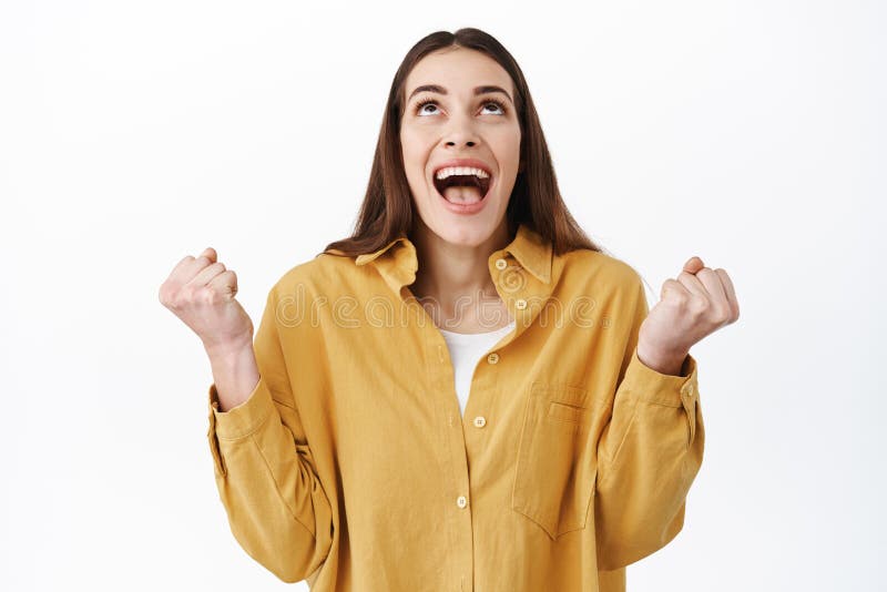 Relieved woman winning, celebrating victory, thanking god and looking up with pleasure and happiness, clench fists