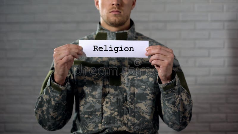 Religion word written on sign in hands of male soldier, faith in God, prayer