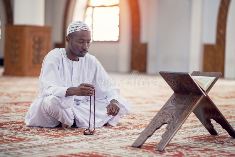 Religious black muslim man praying inside the mosque royalty free stock images