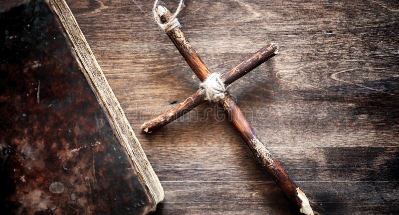 Religious old book on a wooden table. A religious cross tied with a rope and burlap next to bible. Worship, sins and prayer.r