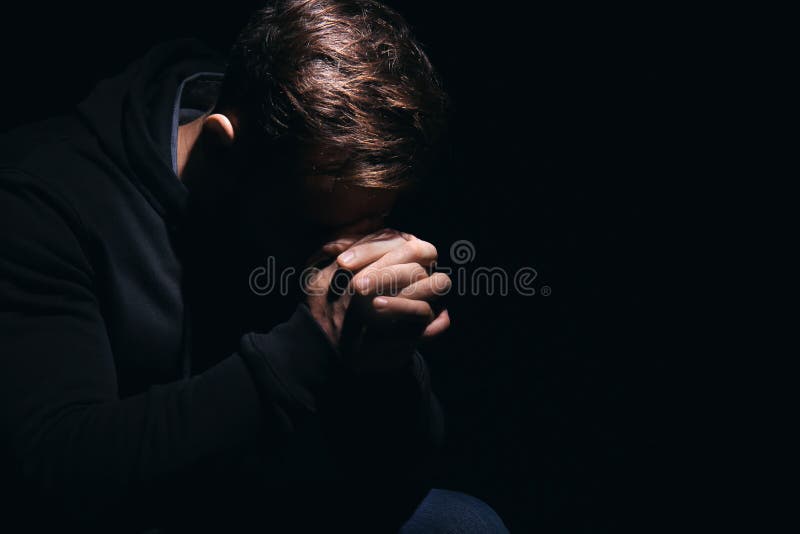 Religious Young Man Praying To God on Black Background Stock Photo