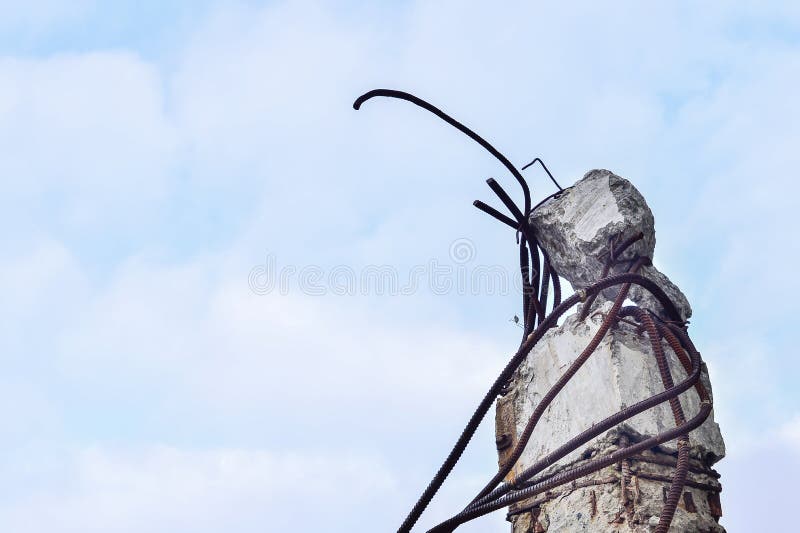 Remains of the destroyed industrial building. A piece of concrete beams with the rebar looks up to the sky.