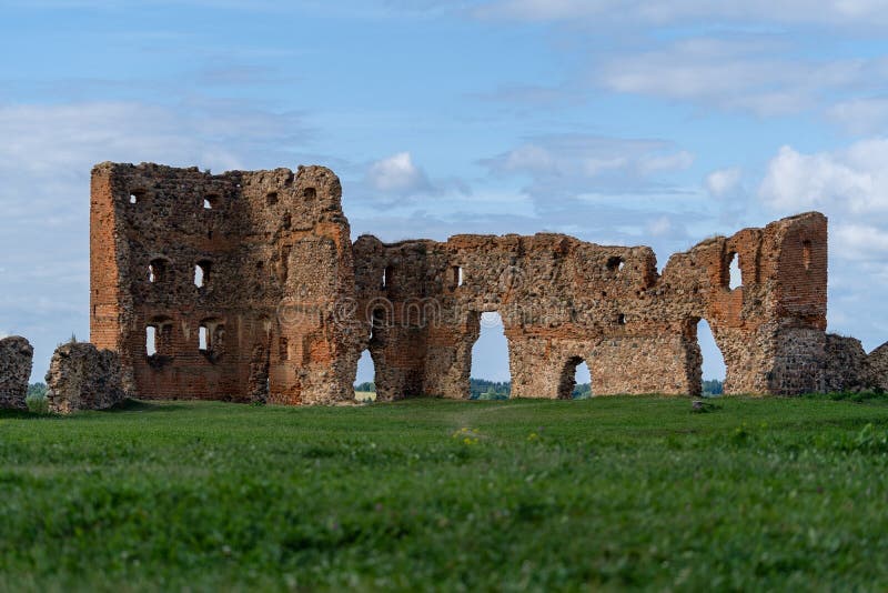 Remains of Ludza castle ruins on the foreground of green grass and blue sky