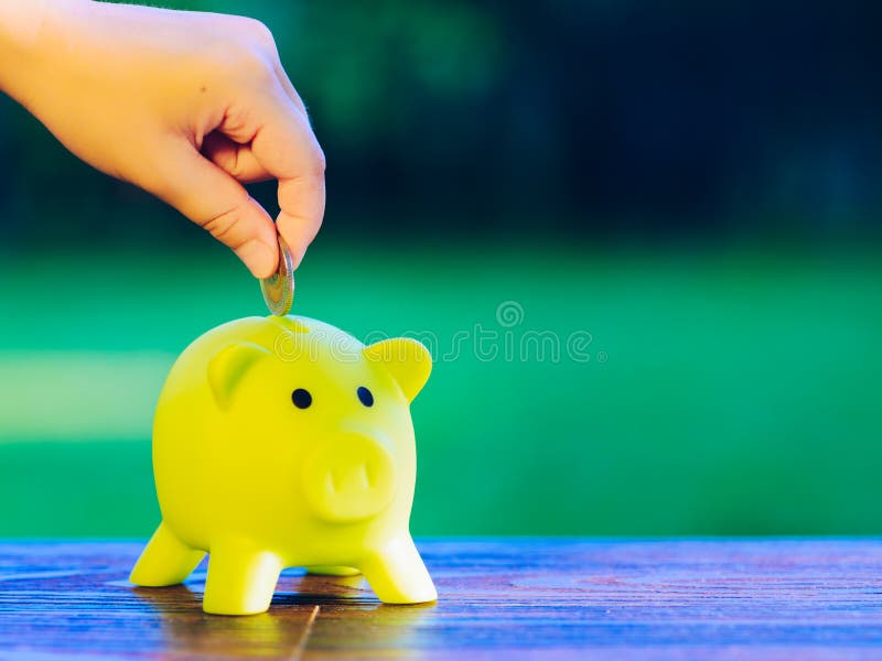 Remettez insérer une pièce de monnaie dans la tirelire verte photos stock