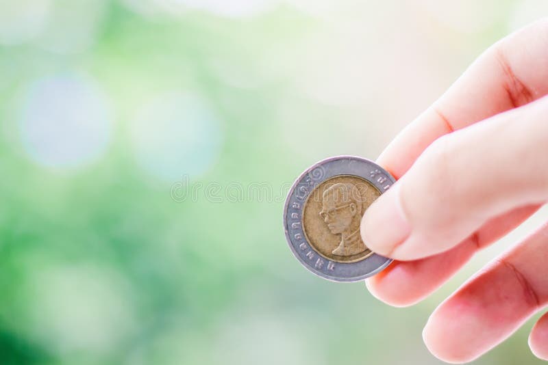 Remettez tenir une pièce de monnaie, argent thaïlandais de devise de 10 bahts photographie stock libre de droits Remettez tenir une pièce de monnaie, argent thaïlandais de devise de 10 bahts photographie stock libre de droits