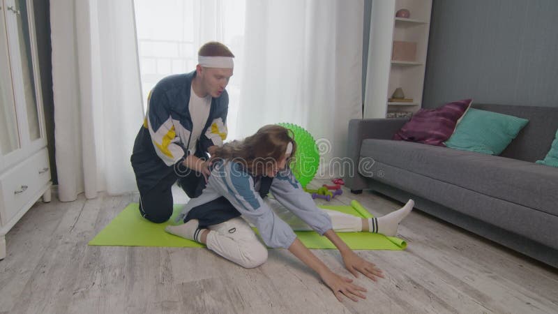 Remise en forme de la famille à la maison. Jeune femme et homme heureux de couples de formation ensemble à la maison. L'homme aide banque de vidéos