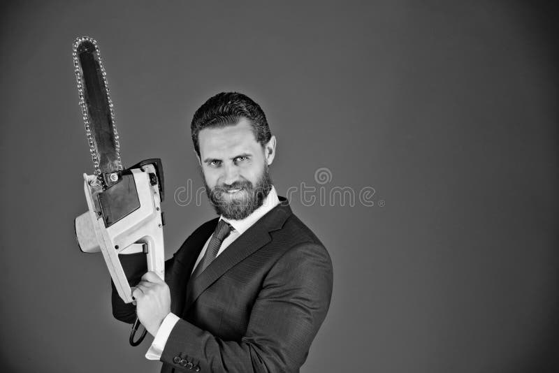 Remises folles jeune homme d'affaires avec la tronçonneuse, homme heureux de sourire dans le costume bleu image stock Remises folles jeune homme d'affaires avec la tronçonneuse, homme heureux de sourire dans le costume bleu image stock