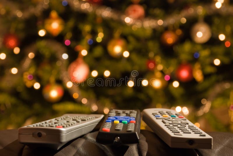 Remote controls in front of lit christmas tree