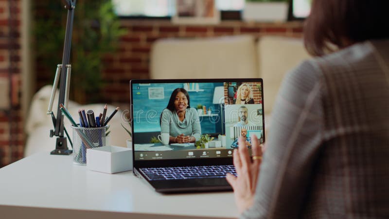 Teleworker in living room chats in teleconference call with business executives