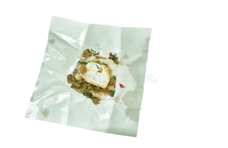 Spicy stir fried chicken thigh with basil leaf topping egg on rice isolated in white paper packing. Spicy stir fried chicken thigh with basil leaf topping egg on rice isolated in white paper packing