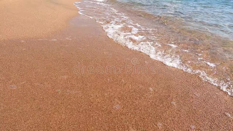 Ren vattenstruktur i blått. kustvåglinje och ren sand. havets bakgrund och havet som är nedblänkt av solen. naturlig grund