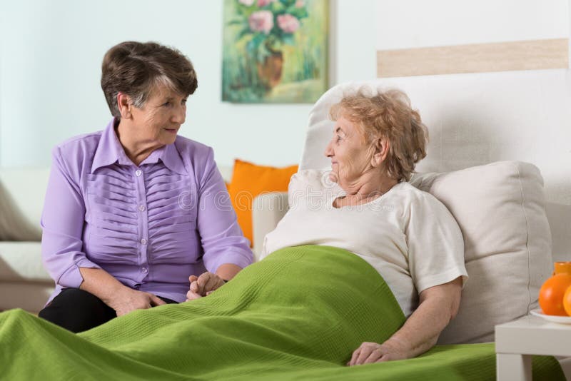 Woman visiting her sick elderly friend. Woman visiting her sick elderly friend