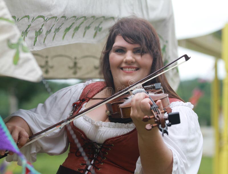 Woman in costume plays a fiddle or violin at a Renaissance fair. Taken at the Whitehart Renaissance Faire, June 14, 2015, Harvtille, Missouri. Woman in costume plays a fiddle or violin at a Renaissance fair. Taken at the Whitehart Renaissance Faire, June 14, 2015, Harvtille, Missouri.