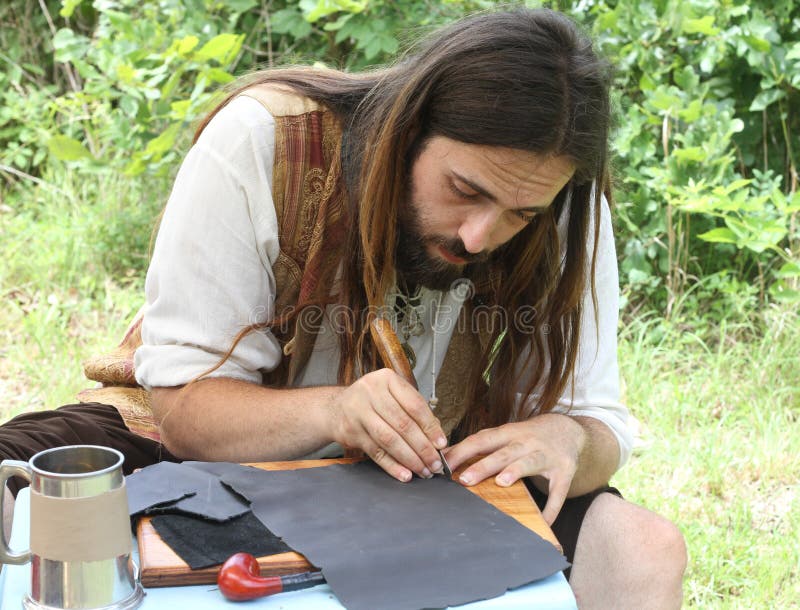 Long-haired Craftsman works with leather at the Whitehart Renaissance Faire, June 14, 2015, Harvtille, Missouri. Long-haired Craftsman works with leather at the Whitehart Renaissance Faire, June 14, 2015, Harvtille, Missouri.