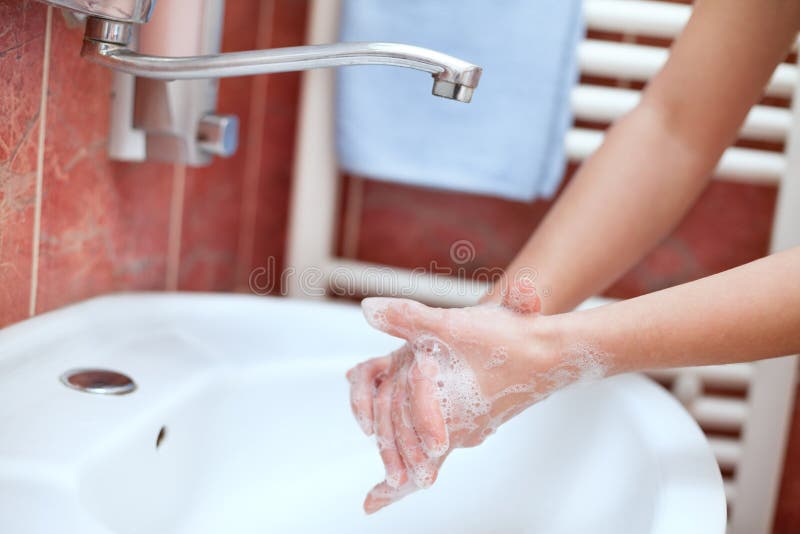 Rengörande händer med tvål under vasken