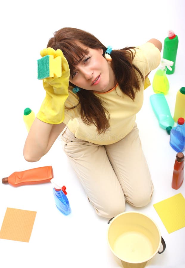 A tired woman of cleaning with sponge in her hand, bottles of household chemistry and bucket isolated on a white background. A tired woman of cleaning with sponge in her hand, bottles of household chemistry and bucket isolated on a white background