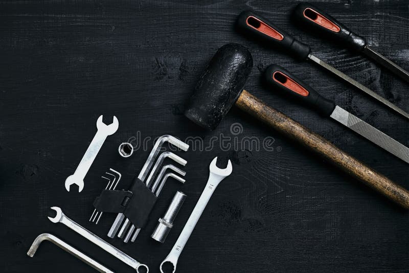 Renovando um carro Um grupo de ferramentas do reparo encanta chaves, um martelo e uma chave de fenda em um fundo de madeira preto imagem de stock Renovando um carro Um grupo de ferramentas do reparo encanta chaves, um martelo e uma chave de fenda em um fundo de madeira preto imagem de stock
