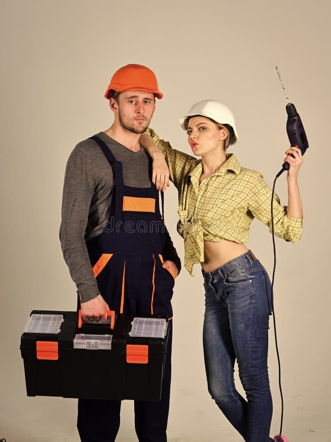Renovation concept. Repairman with girlfriend. Builders with toolbox and drill, couple in love makes repair grey