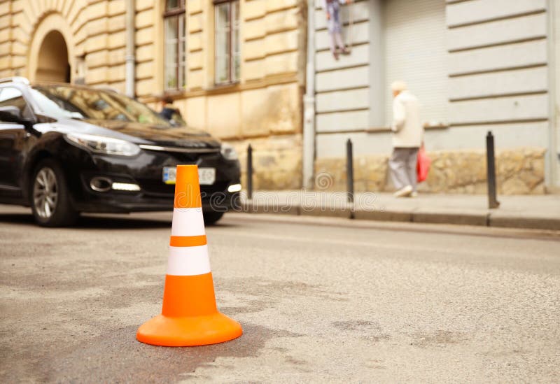 Repair work sign restricting traffic. White-orange plastic striped cone warning of danger. Tightening in traffic. Street of the royalty free stock photography Repair work sign restricting traffic. White-orange plastic striped cone warning of danger. Tightening in traffic. Street of the royalty free stock photography
